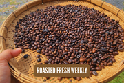 Roasted coffee beans on a woven tray with 'Roasted Fresh Weekly' text.
