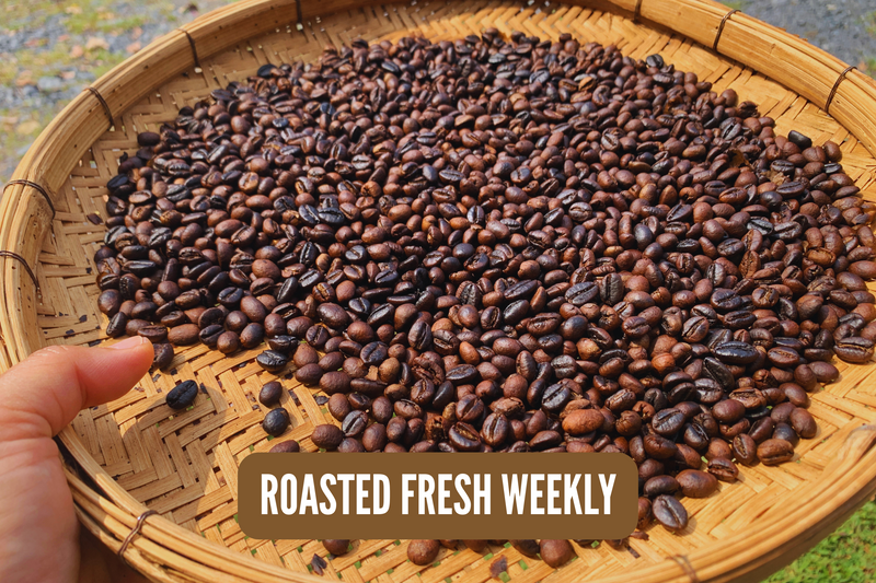 Roasted coffee beans on a woven tray with 'Roasted Fresh Weekly' text.